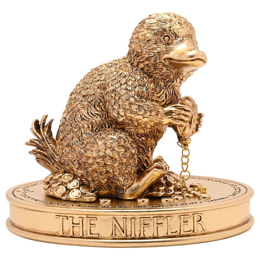Figurine Niffleur dorée Harry Potter entourée de pièces et de trésors avec une chaîne entre ses pattes.