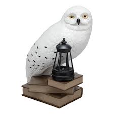 Lampe solaire Hedwige Harry Potter avec lanterne lumineuse posée sur une pile de livres.
