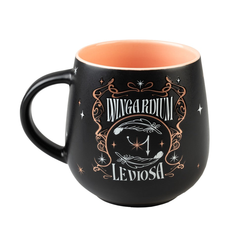 Mug Harry Potter Wingardium Leviosa en céramique noire, intérieur pêche, décoré de plumes blanches, d'étoiles et d'arabesques cuivrées.